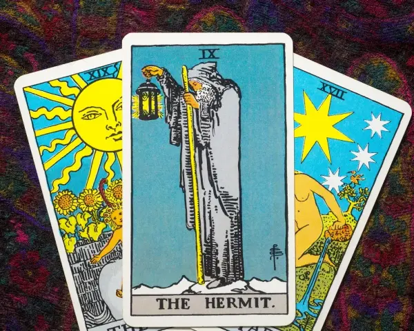 Tarot tak nie: karta Pustelnik w centrum, po bokach Słońce i Gwiazda.