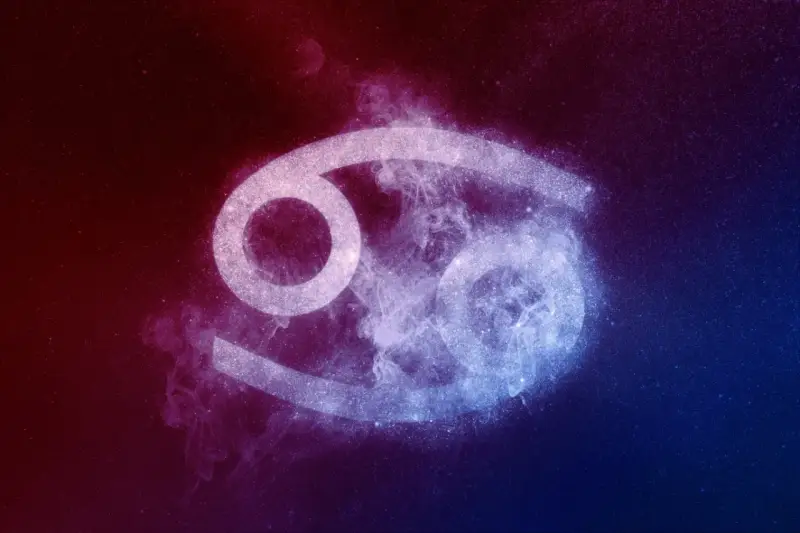 Symbol Raka, 23 czerwca znak zodiaku, otoczony kosmiczną mgławką w odcieniach czerwieni i błękitu.