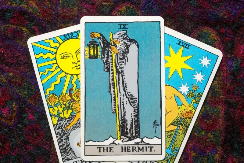 Tarot tak nie: karta Pustelnik w centrum, po bokach Słońce i Gwiazda.